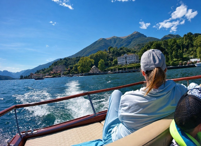 A boat on a lake with mountains and buildings in the background. 2