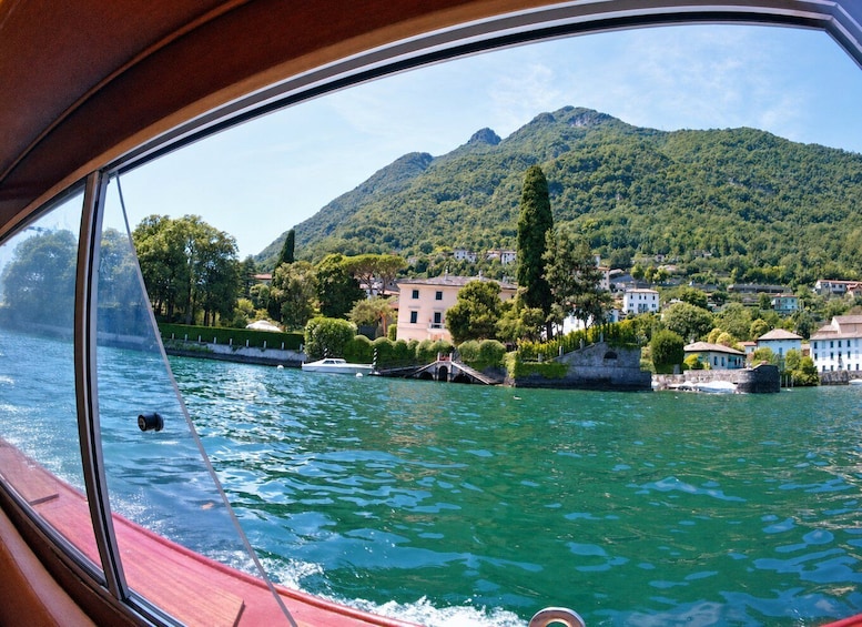 A lake with a boat, a mountain, and buildings along the shore. 1