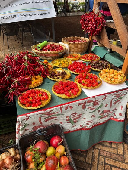 A market stall with various fruits and vegetables, including red chili peppers, strawberries, and pomegranates. 5