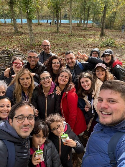 A group of people in a forested area with trees and a blue tarp in the background. 4