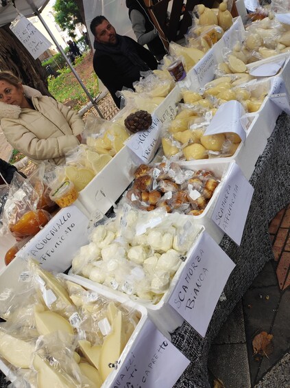 A variety of cheeses and cured meats displayed in plastic containers with labels. 3