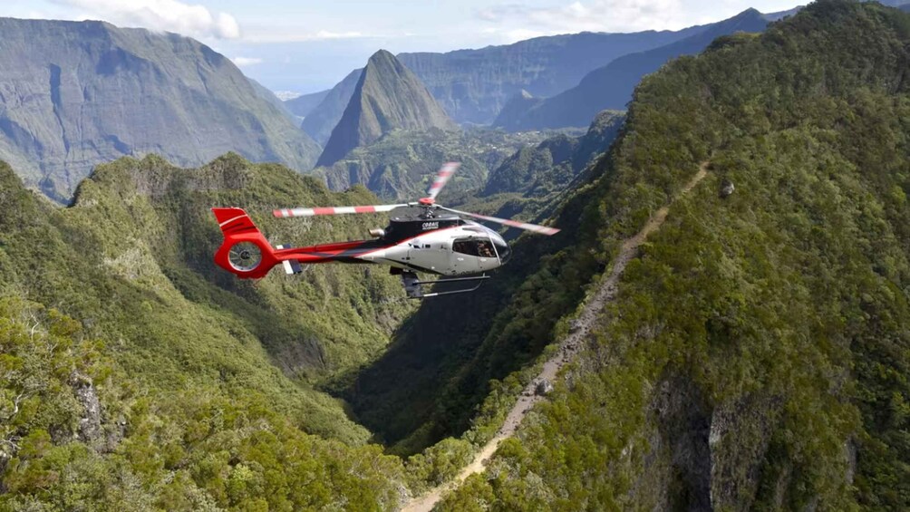 A helicopter flying over a mountainous landscape with a winding road. 3