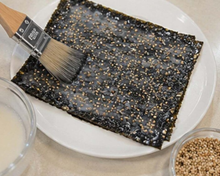 A plate with seaweed, a brush, and a bowl of sesame seeds. 3