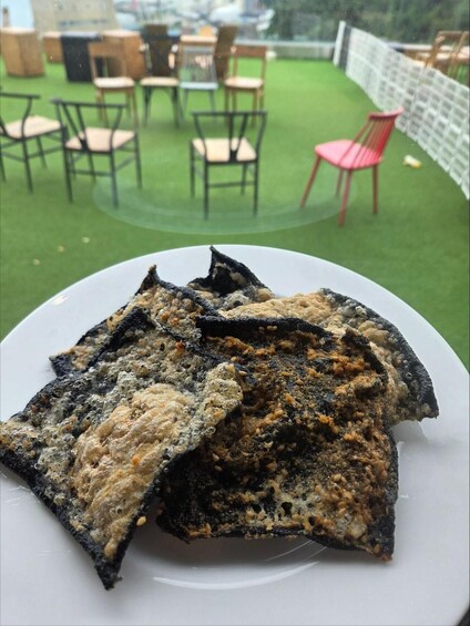 A plate of fried fish with a crispy exterior, set against a backdrop of outdoor dining chairs and tables. 4