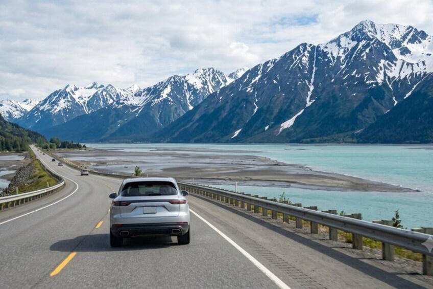 A car driving on a road with mountains and a lake in the background. 4
