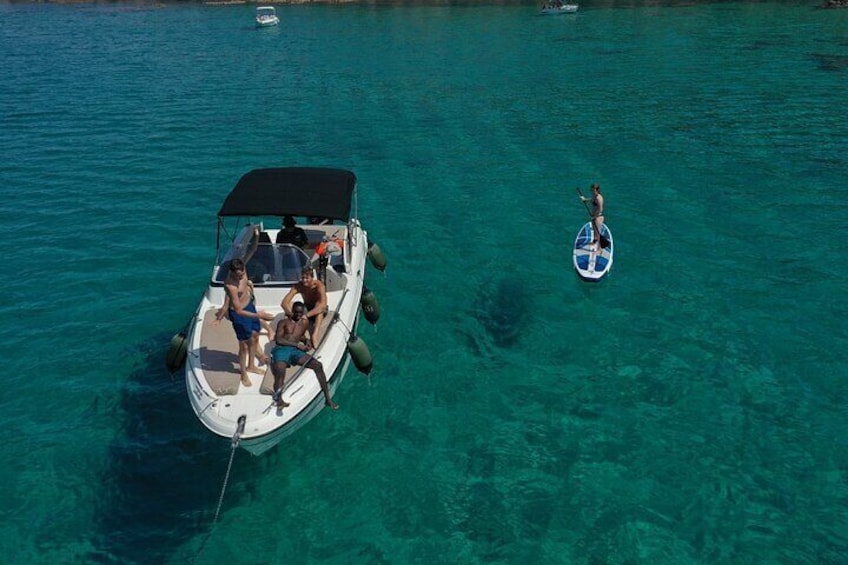 A boat with people on it and a paddleboarder in the water. 4