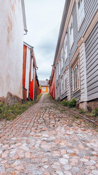 A cobblestone street flanked by buildings with wooden facades and a clear sky. 2