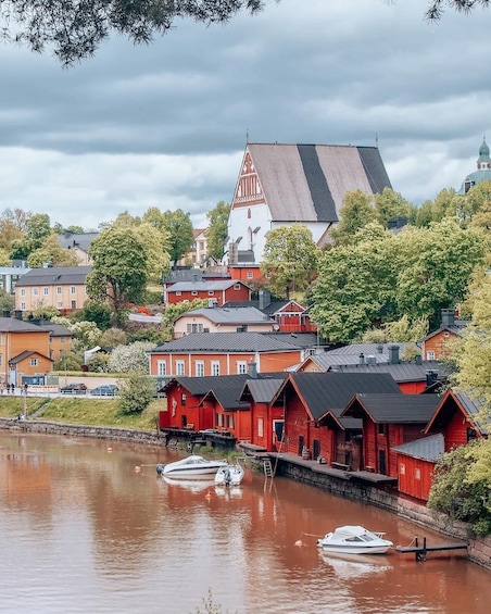 A riverside town with red wooden buildings, a church, and a green dome. 1