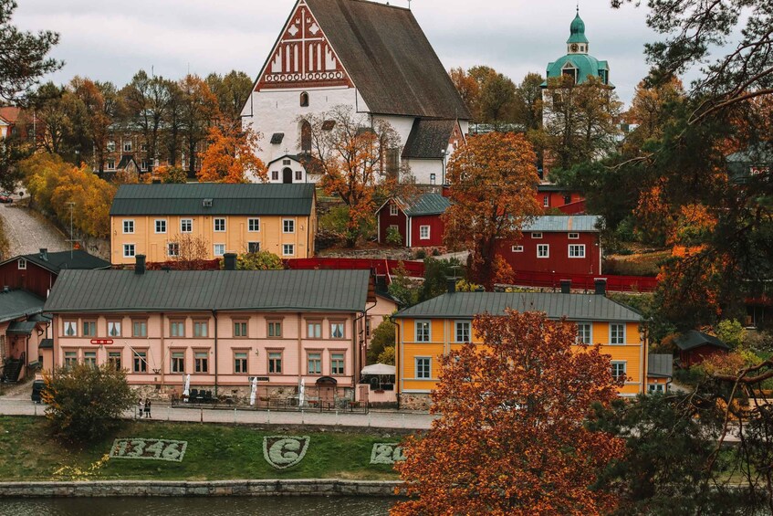 A town with autumn-colored trees, a church with a green dome, and a river. 3