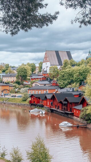 A riverside town with red wooden houses, a church, and a boat docked in the water. 5