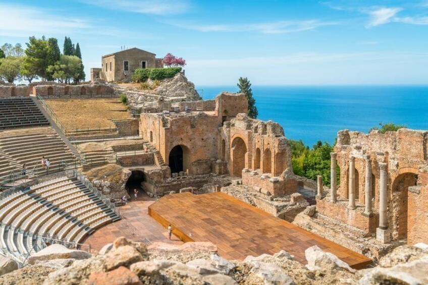 An ancient amphitheater with ruins and a view of the sea. 1