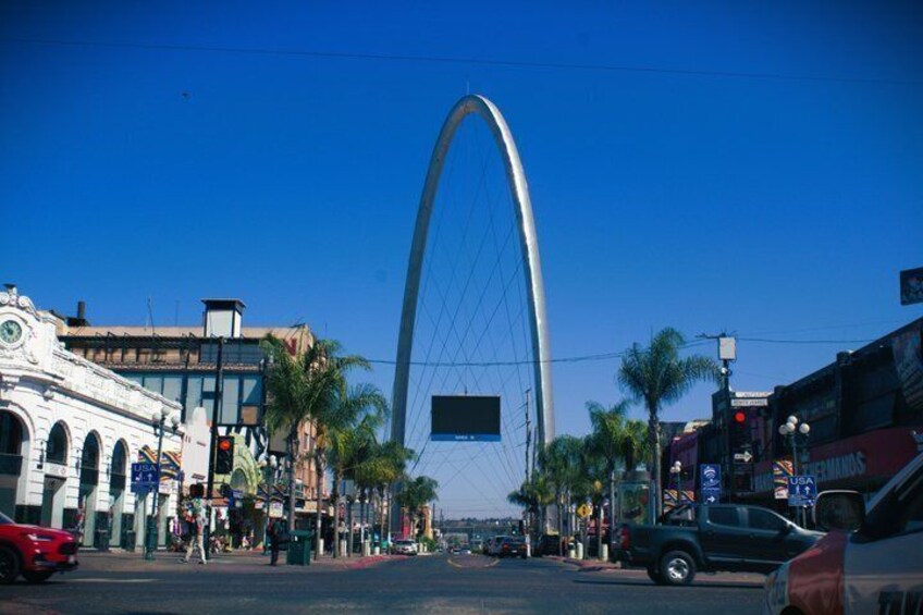 A city street with a prominent arch bridge, palm trees, and various buildings. 1