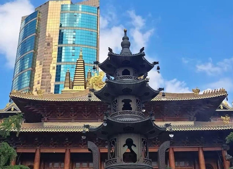 A traditional Chinese pagoda with ornate architecture, a modern glass building in the background, and a clear blue sky. 3