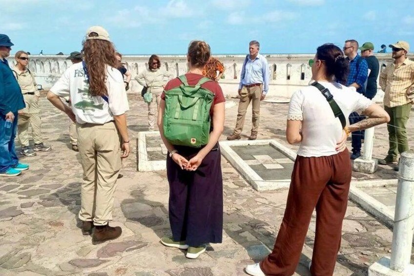 A group of people standing on a stone-paved area with a railing, overlooking a body of water. 3