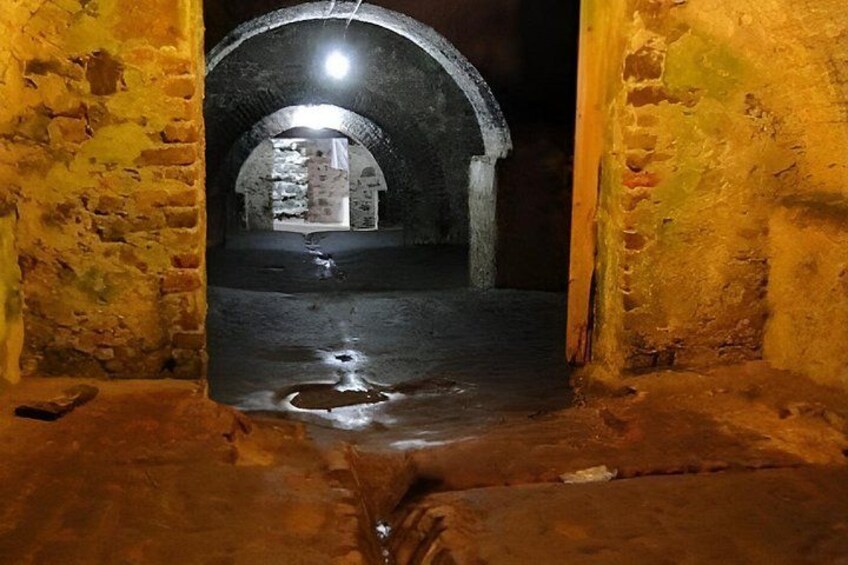 An underground passageway with arched ceilings and a central light source. 3