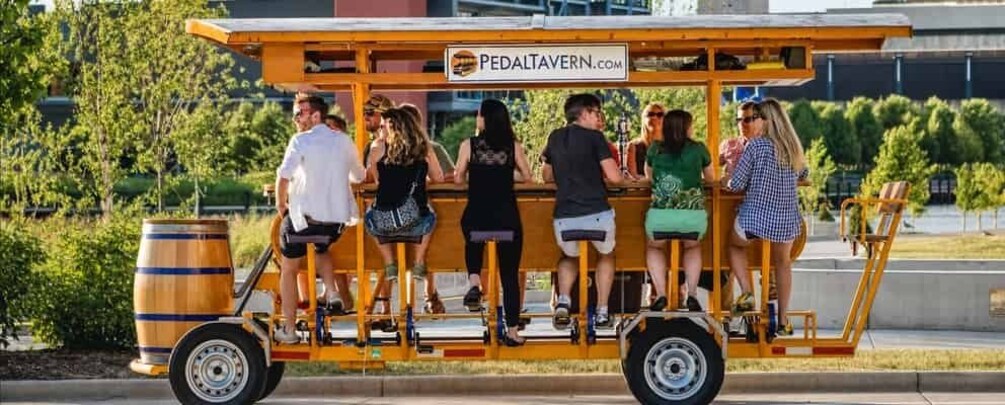 A yellow trolley with people seated, labeled 'PEDALTAVERN.COM', parked on a street. 3