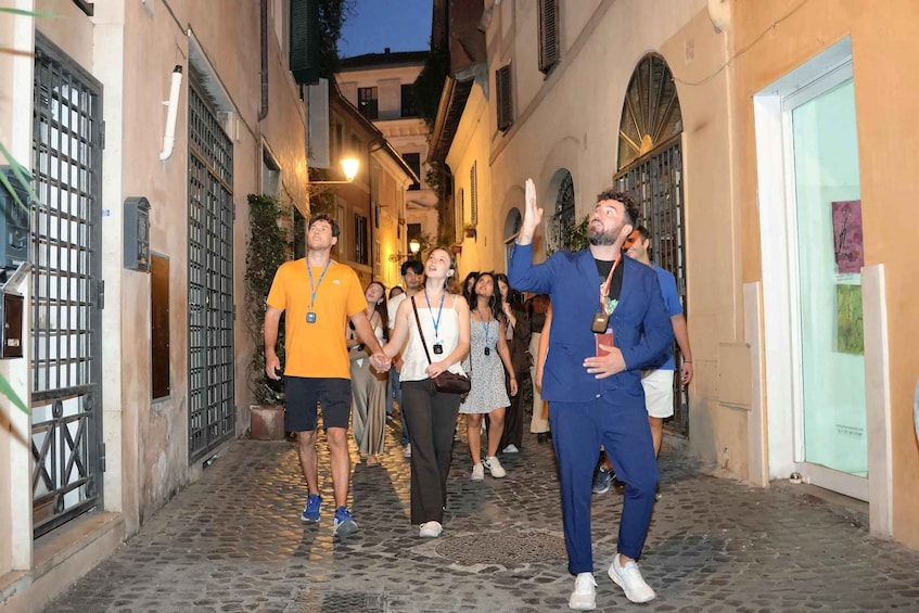 A cobblestone street with buildings on either side, a person gesturing, and several people walking. 3