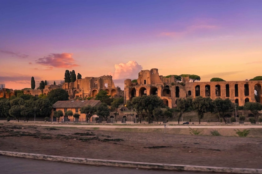 Ancient ruins with arches and columns, surrounded by trees and a small building. 5