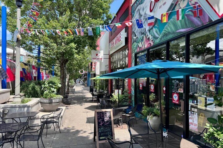 A street with outdoor seating, flags, and a restaurant with a colorful mural. 3