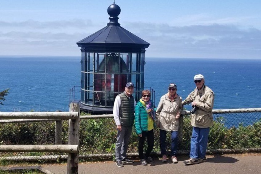 A group of people standing near a glass observation tower overlooking the ocean. 5