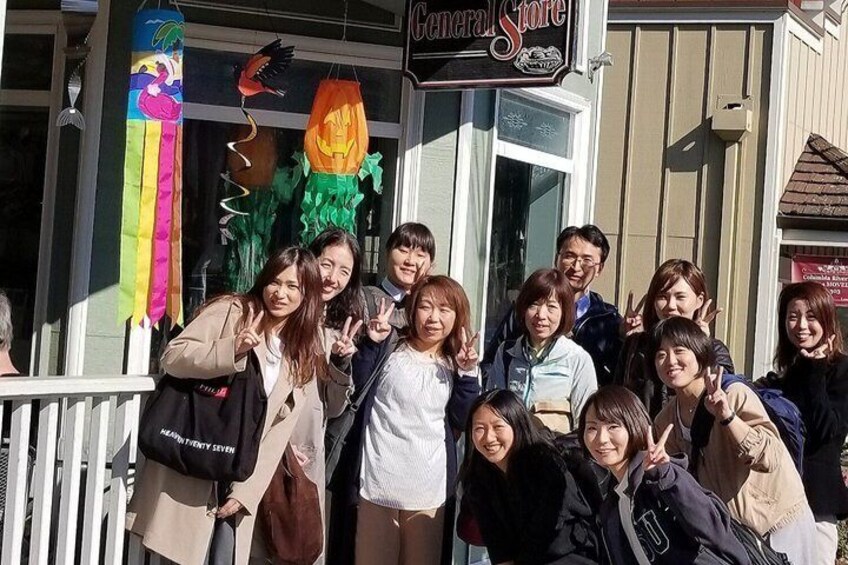 A group of people posing in front of a store with Halloween decorations. 3