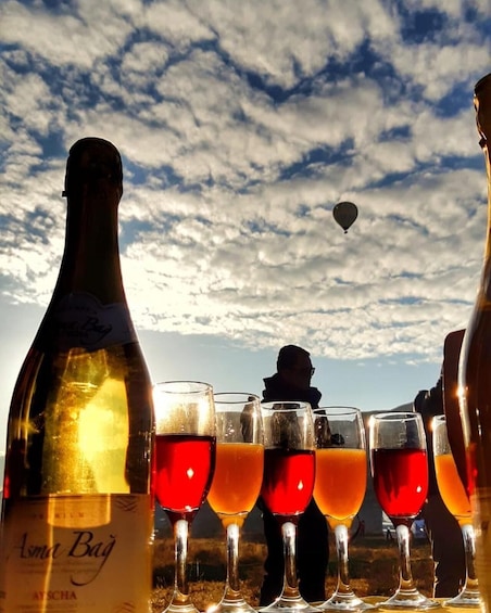 A bottle of wine, glasses of red wine, and a hot air balloon in the sky. 1