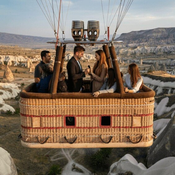 A wicker hot air balloon with passengers, flying over a landscape with rock formations. 4
