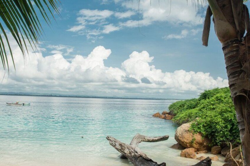A tropical beach with clear turquoise water, a small boat, and lush greenery. 3