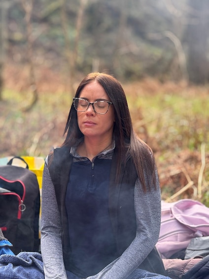 A person sitting outdoors with a backpack and a bag in the background. 1