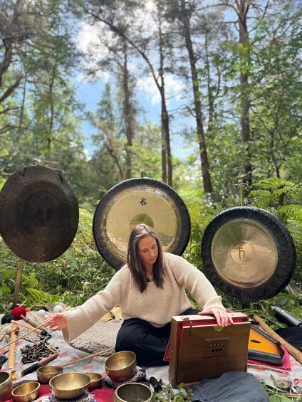 A person sitting outdoors surrounded by various musical instruments and objects. 2