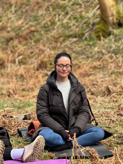 A person sitting cross-legged on a mat outdoors. 3
