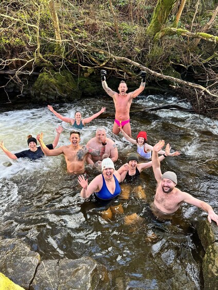 A group of people in a river surrounded by rocks and greenery. 4