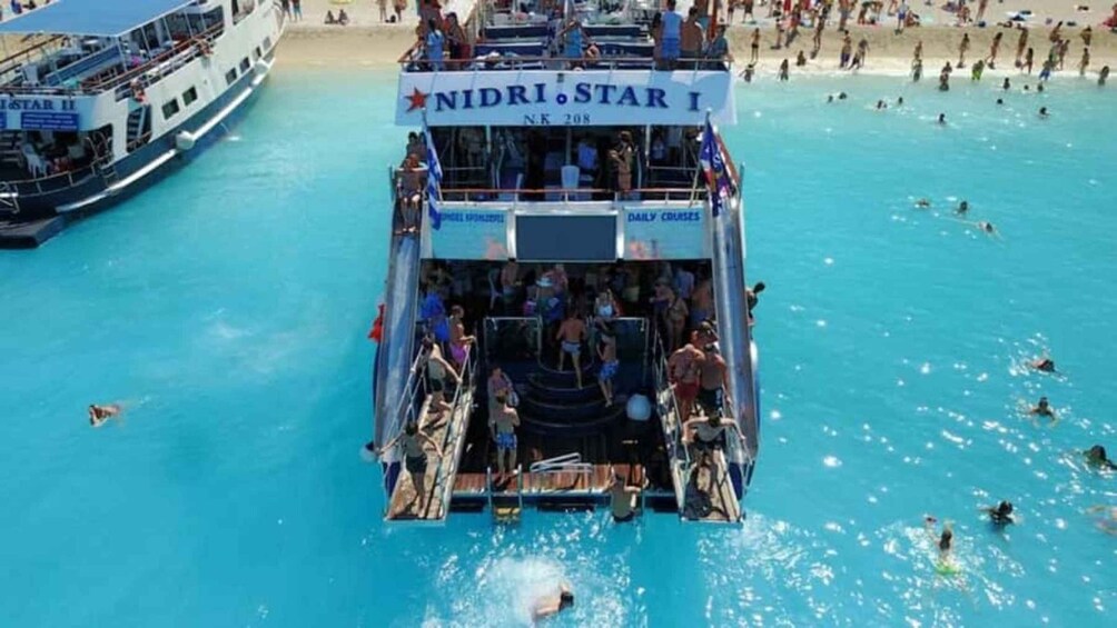 A boat named NIDRI STAR I with people boarding and swimming in the water. 5