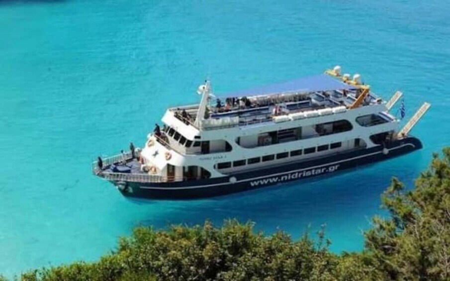 A large boat with a website address on its side, floating on clear blue water. 1