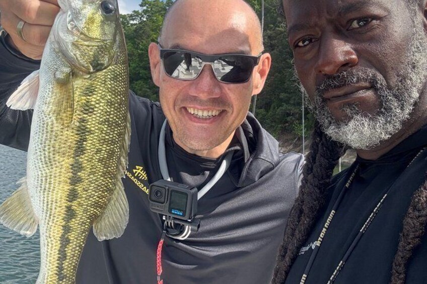 Two individuals holding a fish, with one wearing a camera around their neck. 5