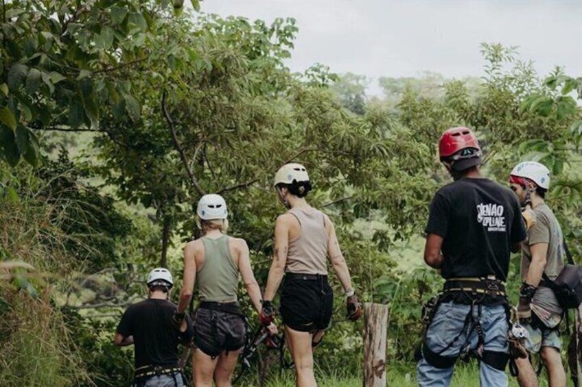A group of people wearing helmets and backpacks, standing in a forested area. 1