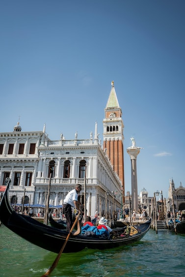 A gondola on Venice's Grand Canal with a historic building and the bell tower of St. Mark's Basilica in the background. 5