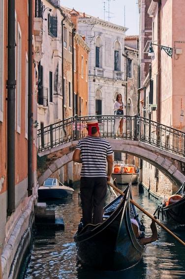 A narrow Venetian canal with gondolas, a bridge, and historic buildings. 2