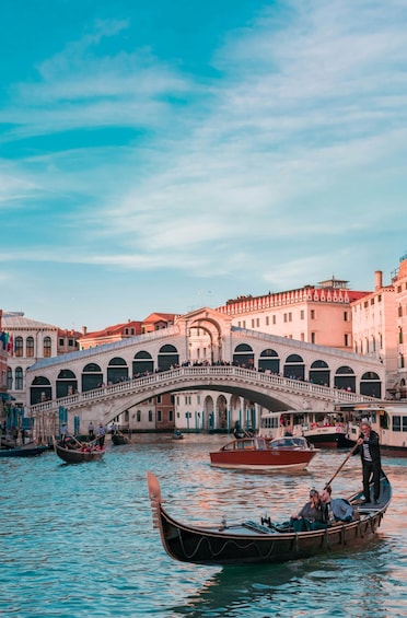 A canal with gondolas, a stone bridge, and historic buildings in the background. 4