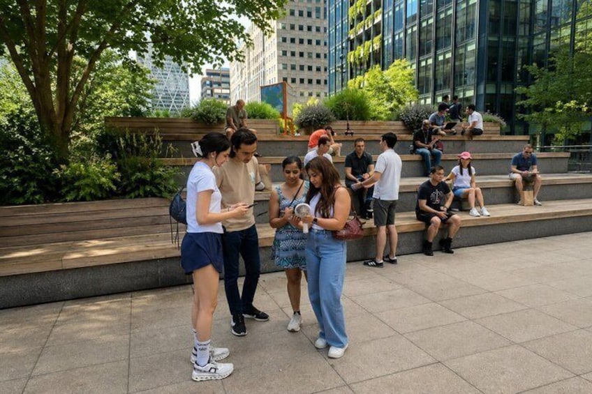 People sitting and standing on outdoor steps, with buildings and trees in the background. 4