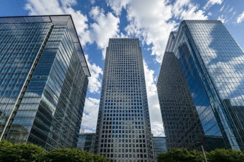 Three modern skyscrapers with reflective glass facades, set against a partly cloudy sky. 2