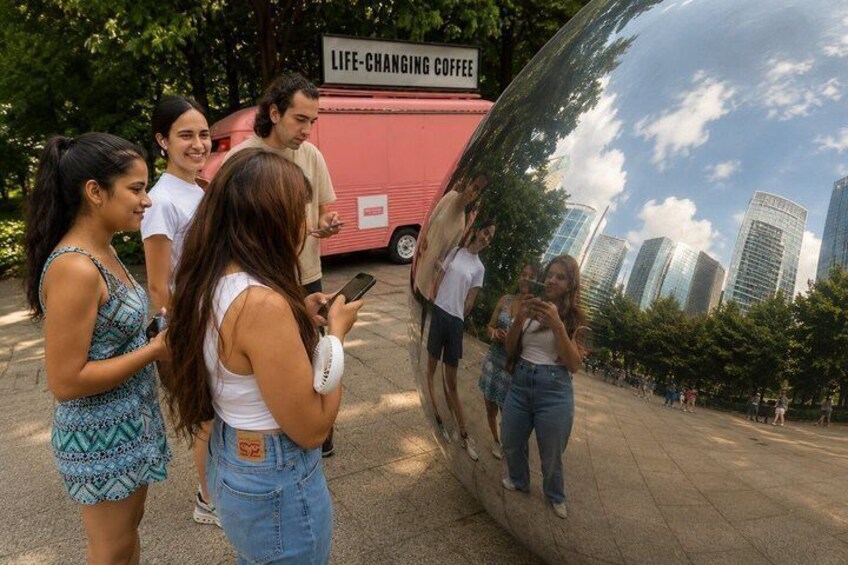 A group of people standing in front of a reflective sphere with a cityscape in the background. 1