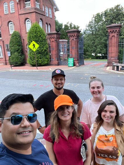A group of people standing in front of a red brick building with arched windows and a pedestrian crossing sign. 1