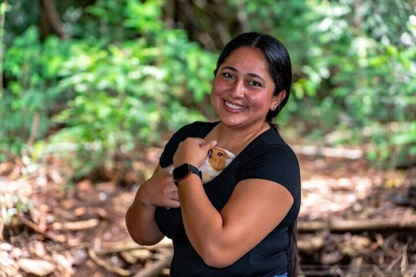 A person holding a small dog in a forested area. 2
