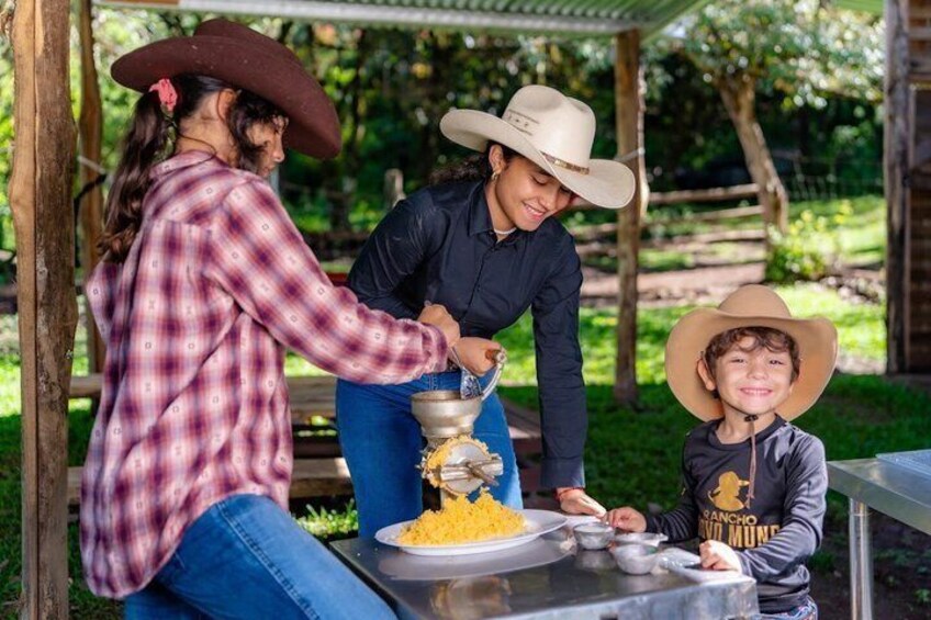 Three people wearing cowboy hats, one adult and two children, preparing food outdoors with a grill and cooking utensils. 1
