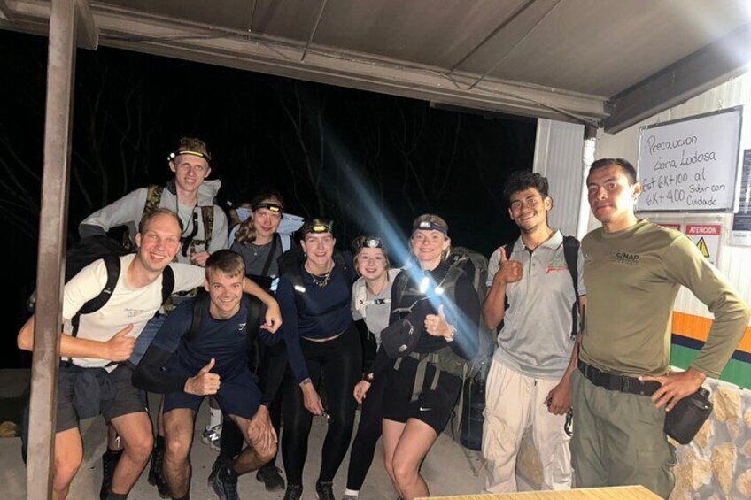 A group of people posing under a shelter at night. 5