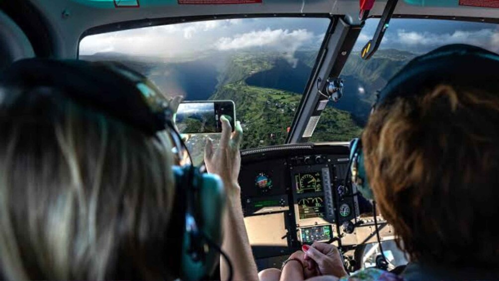 Two people inside a helicopter cockpit, one holding a smartphone. 4