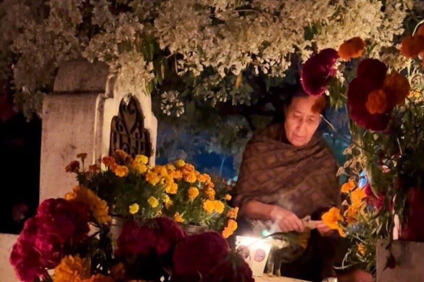 A person lighting candles at a memorial with flowers. 1