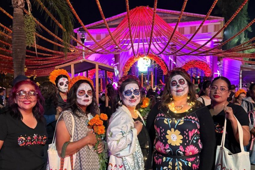 A group of people at a festive outdoor event with arches and string lights. 3
