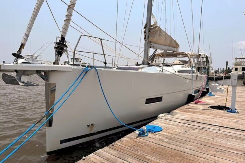 A white sailboat docked at a wooden pier with a blue rope tied to its side. 3